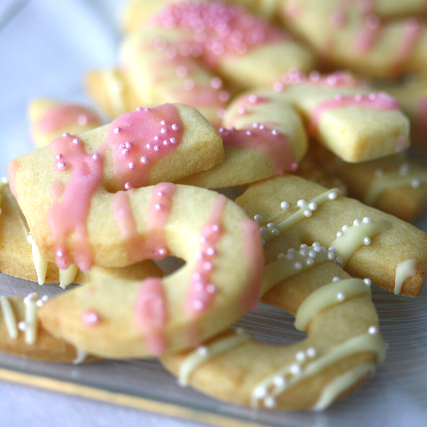 Passend für kleine Ballerinas - Geburtstagsplätzchen mit rosafarbener und weißer Deko und süßen Perlen. Foto: Fräulein Kuchenzauber