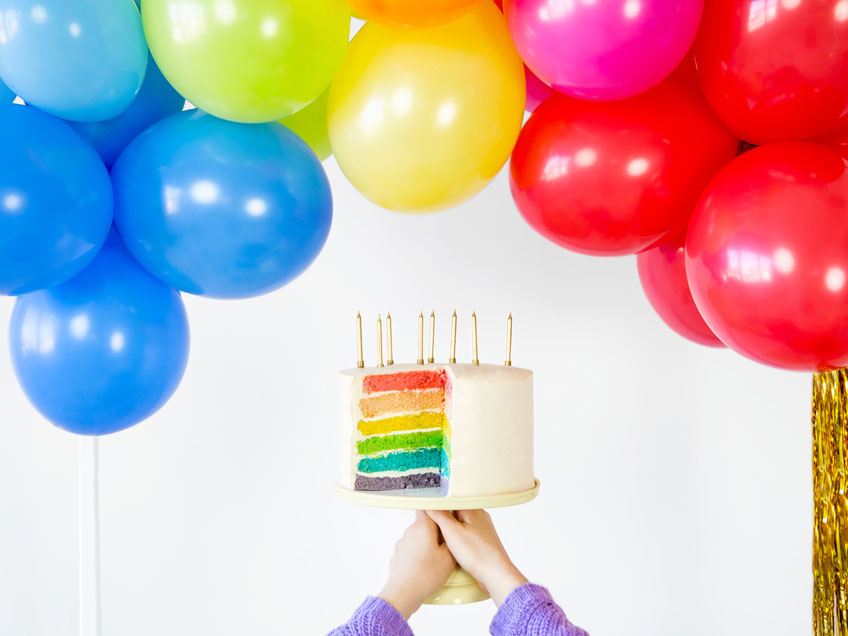 Back eine bunte Regenbogentorte für die Mottoparty