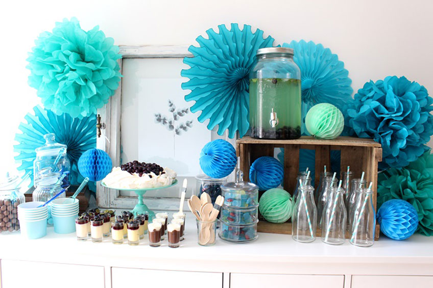 Der Sweet Table in Aqua Farben ist raffiniert in Szene gesetzt. Papierfächer, Pom Poms und Wabenbälle zaubern wunderschöne Effekte auf euren Sweet Table.