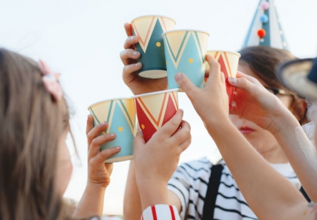 Bunt gemustert wie ein Clownskostüm dient der Pappbecher als Becher und Dose für Dosenwerfen in einem
